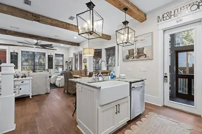 an open kitchen and living room with white walls and wooden ceilings at Let It Be in Inlet Beach