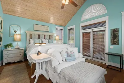 a bedroom with a white bed and a white chair at Let It Be in Inlet Beach
