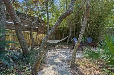a hammock in a garden with trees and a fence at Let It Be in Inlet Beach