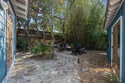 a backyard with a table and chairs and trees at Let It Be in Inlet Beach