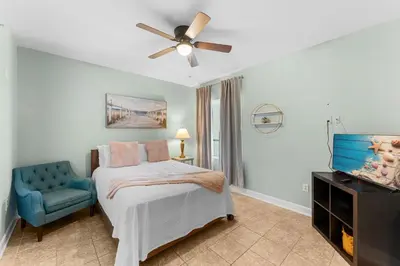 a bedroom with a bed with a ceiling fan and a blue chair at Stunning 3BR Corner Tidewater Resort Beachfront Condo! Sleeps 10! by Dolce Vita Getaways PCB! in Panama City Beach