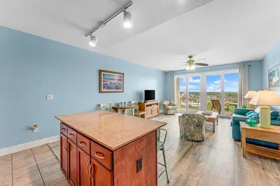 a living room with blue walls and a kitchen with a table at Family and Friends Beach Resort Condo for 8! Steps from the Beach! By Dolce Vita Getaways! in Panama City Beach