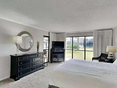 a bedroom with a bed and a tv and a mirror at Edgewater Villa #2601 in Panama City Beach