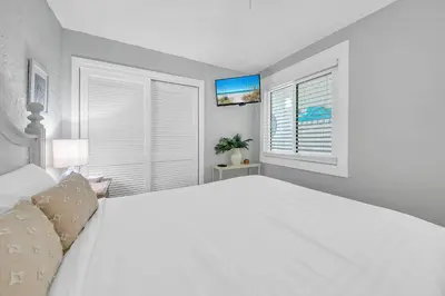 a white bedroom with a large bed and a window at Sugar Beach Condo B-14 by Emerald Coast Retreats in Panama City Beach