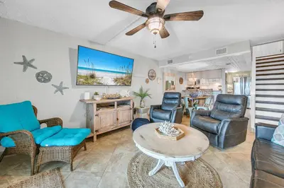 a living room with chairs and a table and a ceiling fan at Sugar Beach Condo B-14 by Emerald Coast Retreats in Panama City Beach