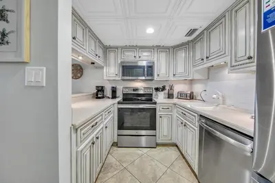 a kitchen with white cabinets and a stove top oven at Sugar Beach Condo B-14 by Emerald Coast Retreats in Panama City Beach