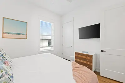 a white bedroom with a bed and a tv at Take It Easy by Book That Condo in Panama City Beach