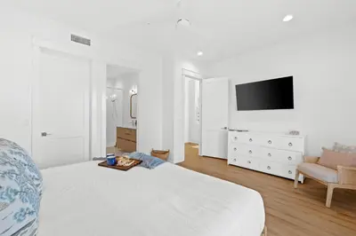a white bedroom with a bed and a tv at Take It Easy by Book That Condo in Panama City Beach