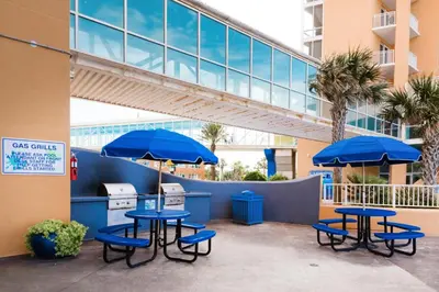 two tables and chairs with blue umbrellas in front of a building at Splash 507E in Panama City Beach