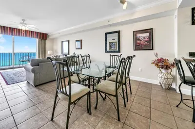 a dining room and living room with a glass table and chairs at Tidewater 1902 in Panama City Beach