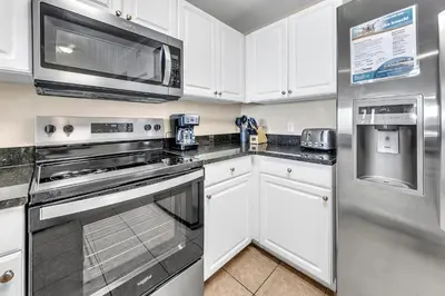 a kitchen with white cabinets and stainless steel appliances at Tidewater 1902 in Panama City Beach