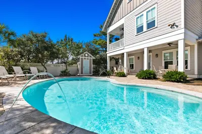 a swimming pool in front of a house at Forever Five O'Clock in Seacrest