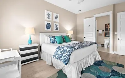 a bedroom with a bed with blue and white pillows at Forever Five O'Clock in Seacrest