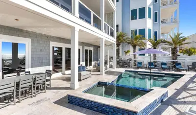 an outdoor patio with a swimming pool and a building at Sunset Serenity in Panama City Beach
