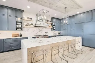 a kitchen with blue cabinets and a large island with stools at Sunset Serenity in Panama City Beach