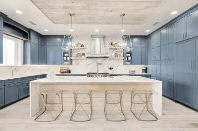 a kitchen with blue cabinets and a large island with bar stools at Sunset Serenity in Panama City Beach