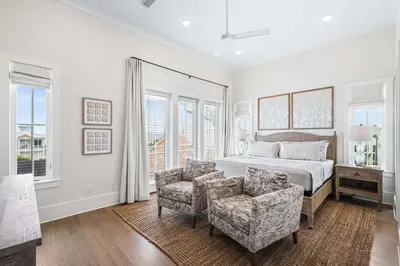 a bedroom with a bed and a chair and windows at Stars on the Water in Santa Rosa Beach