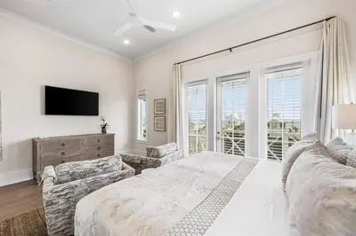 a white bedroom with a bed and a tv at Stars on the Water in Santa Rosa Beach