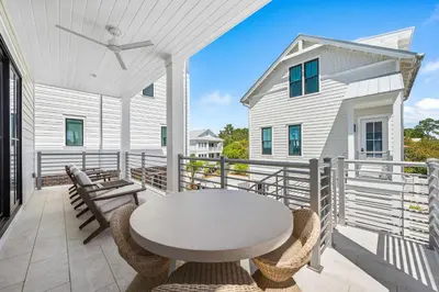 a patio with a table and chairs on a balcony at 30A Sunset 6 Bedroom in Santa Rosa Beach