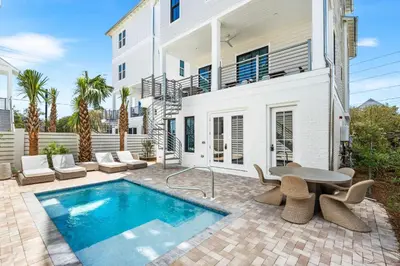 a patio with a pool and a table and chairs at 30A Sunset 6 Bedroom in Santa Rosa Beach