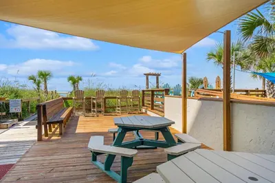 a wooden deck with a picnic table and benches at Moondrifter #803 in Panama City Beach