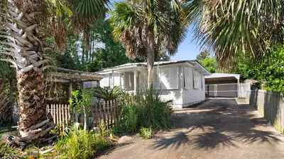 a white house with a fence and palm trees at Vintage Waves in Laguna Beach