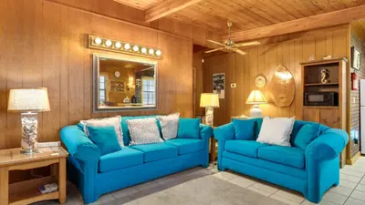 a living room with blue furniture and wooden walls at Vintage Waves in Laguna Beach