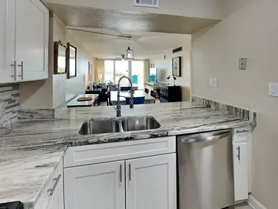 a kitchen with a sink and a living room at Dunes of Panama #B203 in Panama City Beach
