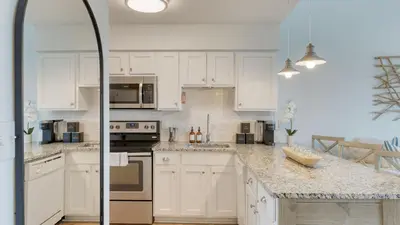 a white kitchen with white cabinets and appliances at Ocean View Balcony Heated Pool Steps to the Beach The Sea Chord by AvantStay in Santa Rosa Beach