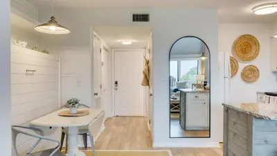 a kitchen and dining room with a table and a mirror at Ocean View Balcony Heated Pool Steps to the Beach The Sea Chord by AvantStay in Santa Rosa Beach