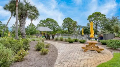 a park with a picnic table and a yellow umbrella at Ocean View Balcony Heated Pool Steps to the Beach The Sea Chord by AvantStay in Santa Rosa Beach