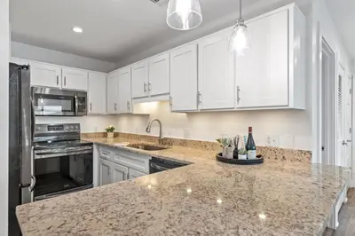 a kitchen with white cabinets and a granite counter top at Beach Condo with Heated POOL and Tennis Courts and Beach Access and 6 Beds that Sleep 8 in Santa Rosa Beach