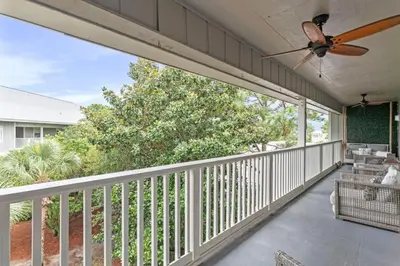 a porch with a ceiling fan and a balcony with chairs at Beach Condo with Heated POOL and Tennis Courts and Beach Access and 6 Beds that Sleep 8 in Santa Rosa Beach