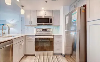 a kitchen with white cabinets and a stainless steel appliances at Sunbird Resort! Stunning Remodeled Beachfront Condo! Free Beach Chair Service! by Dolce Vita PCB! in Panama City Beach