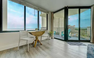 a dining room with large windows and a table and chairs at Sunbird Resort! Stunning Remodeled Beachfront Condo! Free Beach Chair Service! by Dolce Vita PCB! in Panama City Beach