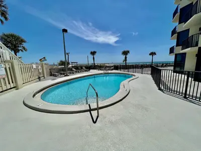 a swimming pool next to a building and the ocean at Sunbird Resort! Stunning Remodeled Beachfront Condo! Free Beach Chair Service! by Dolce Vita PCB! in Panama City Beach