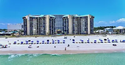 a beach with chairs and umbrellas in front of a hotel at Sunbird Resort! Stunning Remodeled Beachfront Condo! Free Beach Chair Service! by Dolce Vita PCB! in Panama City Beach