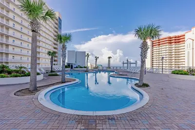 a swimming pool with palm trees and buildings at Spectacular Ocean View Condo! Steps to the Beach! by Dolce Vita Getaways PCB! in Panama City Beach