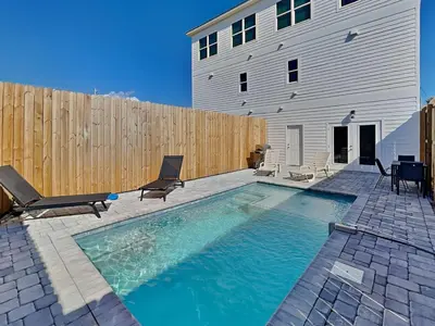 a swimming pool with chairs and a wooden fence at Sunset On Snapper A in Panama City Beach