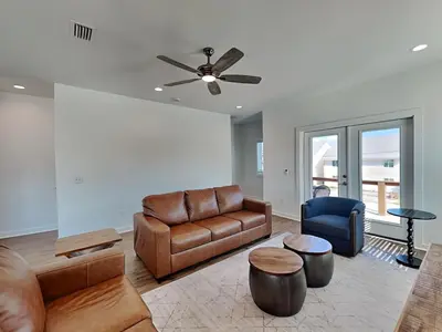 a living room with leather furniture and a ceiling fan at Sunset On Snapper A in Panama City Beach