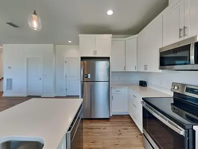 a kitchen with white cabinets and a stainless steel refrigerator at Sunset On Snapper B in Panama City Beach