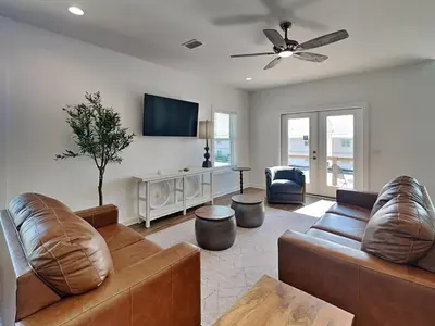 a living room with two leather couches and a flat screen tv at Sunset On Snapper B in Panama City Beach