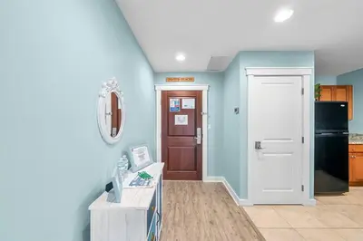 a hallway with blue walls and a white door at Origin 1227 Beachy Dreams in Panama City Beach