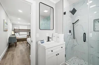a white bathroom with a shower and a sink at Beach House - Barefoot House by Panhandle Getaways in Panama City Beach