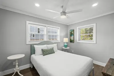 a bedroom with a white bed and two windows at Beach House - Barefoot House by Panhandle Getaways in Panama City Beach