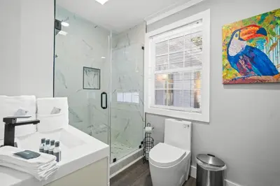 a white bathroom with a shower and a toilet at Beach House - Barefoot House by Panhandle Getaways in Panama City Beach