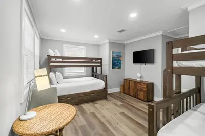 a bedroom with two bunk beds and a television at Beach House - Barefoot House by Panhandle Getaways in Panama City Beach