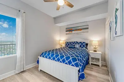 a bedroom with a blue and white bed and a window at Stunning Beachfront 