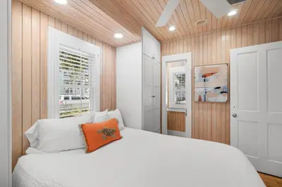 a bedroom with a white bed with an orange pillow at Carillon Beach House - Grits Carlton by Panhandle Getaways in Panama City Beach