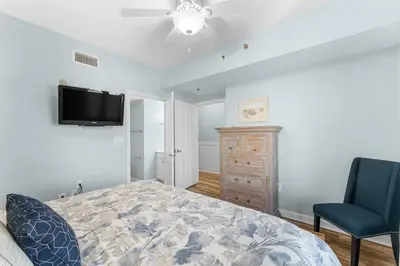a bedroom with a bed and a tv and a chair at Shores Of Panama #0526 in Panama City Beach